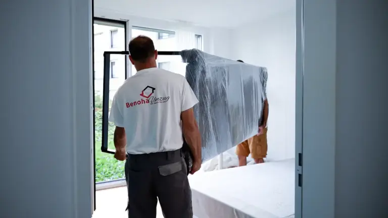 Benoha-Mitarbeiter trägt ein verpacktes Möbelstück aus der Wohnung
