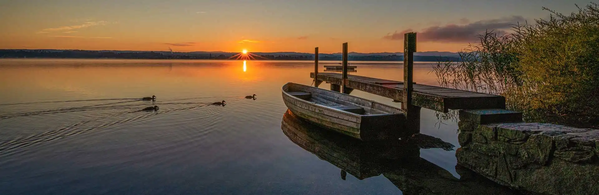 Umzug in Nänikon und Greifensee: Ruderboot am Steg im Greifensee bei Sonnenaufgang